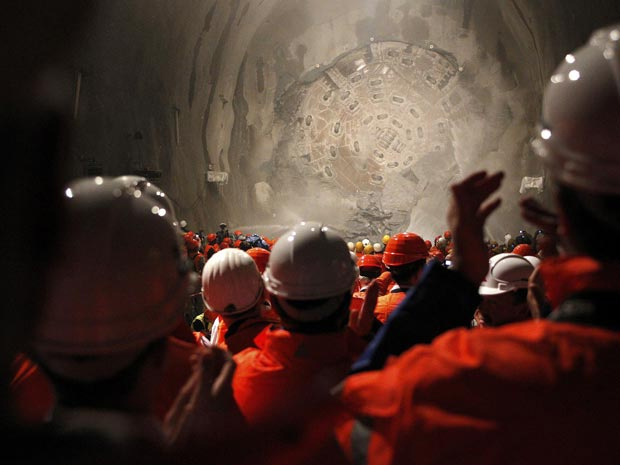 Mineiros observam a perfuradora Sissi romper a rocha no fim do trecho Faido-Sedrun, no local da construção do túnel. (Foto: AP)