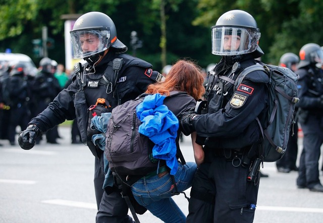 Policial retira manifestante que bloqueava rua em Hamburgo, na Alemanha, nesta sexta-feira (7) (Foto: Hannibal Hanschke/ Reuters)