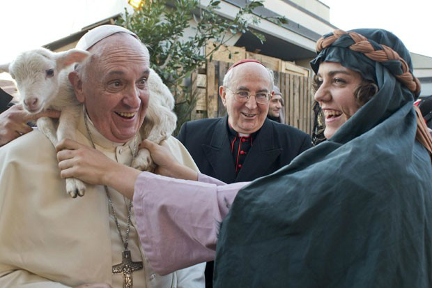 Mulher vestida como personagem da cena do nascimento de Jesus Cristo coloca um carneirinho sobre os ombros do Papa Francisco, na chegada do Pontífice à igreja de St Alfonso Maria dei Liguori, perto de Roma. O Papa reagiu sorrindo à 'carona' inusitada. (Foto: Reuters/Osservatore Romano)
