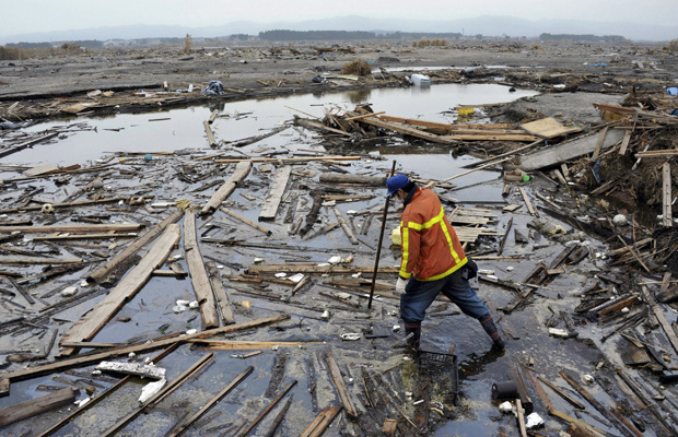 Integrante de equipes de resgate busca corpos em Minami Sota, dentro da zona de exclusão da usina de Fukushima Daiichi, neste sábado (9) (Foto: AP)
