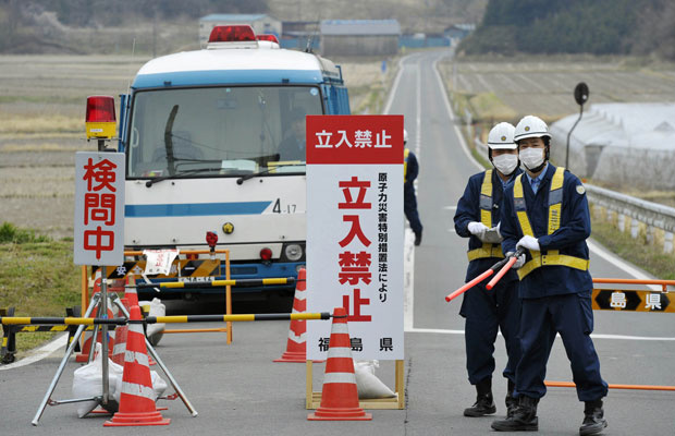 Policiais inspecionam homem em Minamisoma, a cerca de 20km da usina de Fukushima (Foto: AP)