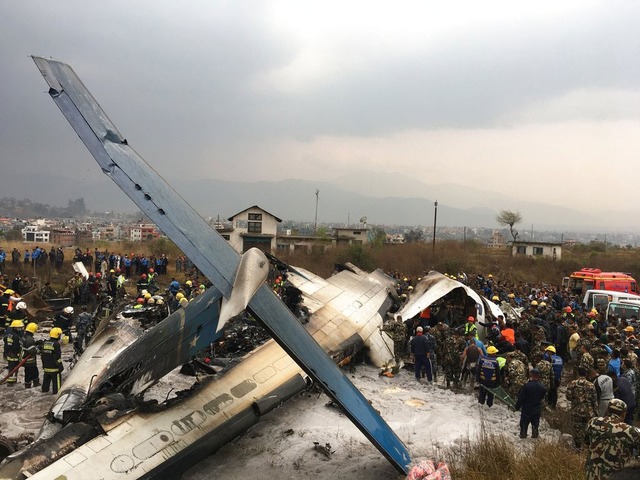 Equipes de resgate trabalham após avião cair no aeroporto de Katmandu, no Nepal, na manhã desta segunda-feira (12) (Foto: Niranjan Shreshta/ AP)