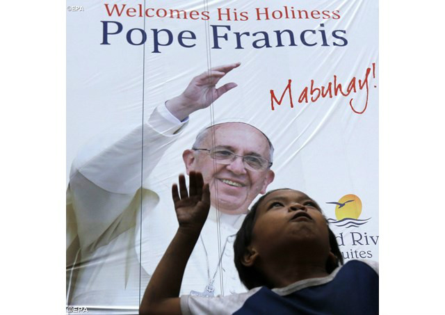 Criança filipina brinca diante de um outdoor de boas-vindas ao Papa Francisco - EPA