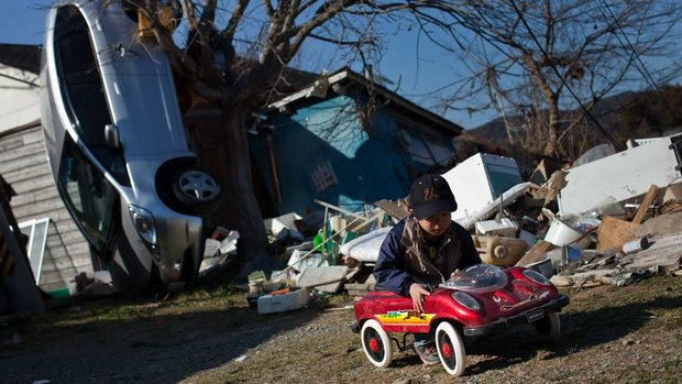 Criança brinca em meio aos destroços da cidade de Ishinomaki, Japão (Yasuyoshi Chiba/AFP)