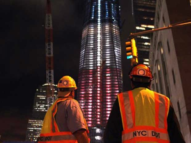 Trabalhadores observam as cores da bandeira dos Estados Unidos projetadas na Freedom Tower, que fica na região onde estavam as Torres Gêmeas, em Nova York. O país se prepara para o 10 º aniversário da tragédia provocada pelos ataques terroristas ao World (Foto: Spencer Platt / Getty Images / AFP Photo)