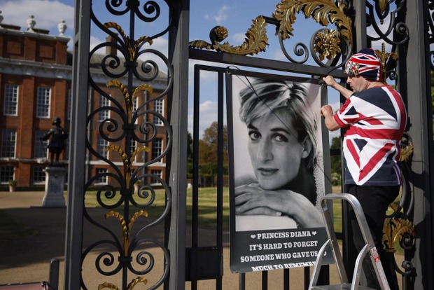 John Loughrey, superfã da princesa Diana, cola um cartaz nas grades do Palacio de Kensington, em Londres, na Inglaterra, em homenagem aos 25 anos da morte dela