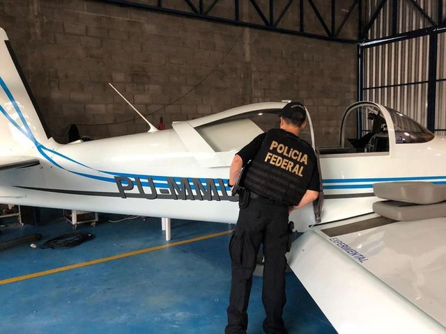 Policial observa aeronave apreendida durante operação Flak     (Polícia Federal/divulgação)