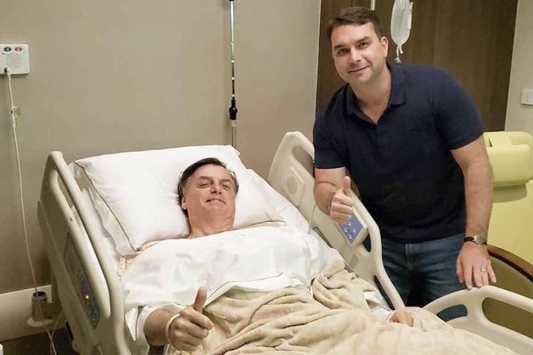 Presidente Jair Bolsonaro co0m o Filho Flavio Bolsonaro, após cirurgia. Twitter 